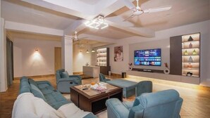 Un salon moderne comprenant un ensemble de canapés, une table basse et un téléviseur. On y trouve également des ventilateurs de plafond et un éclairage encastré.