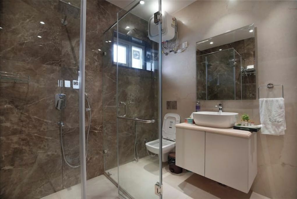 A modern bathroom with a glass-enclosed shower, a white sink, and a large mirror.