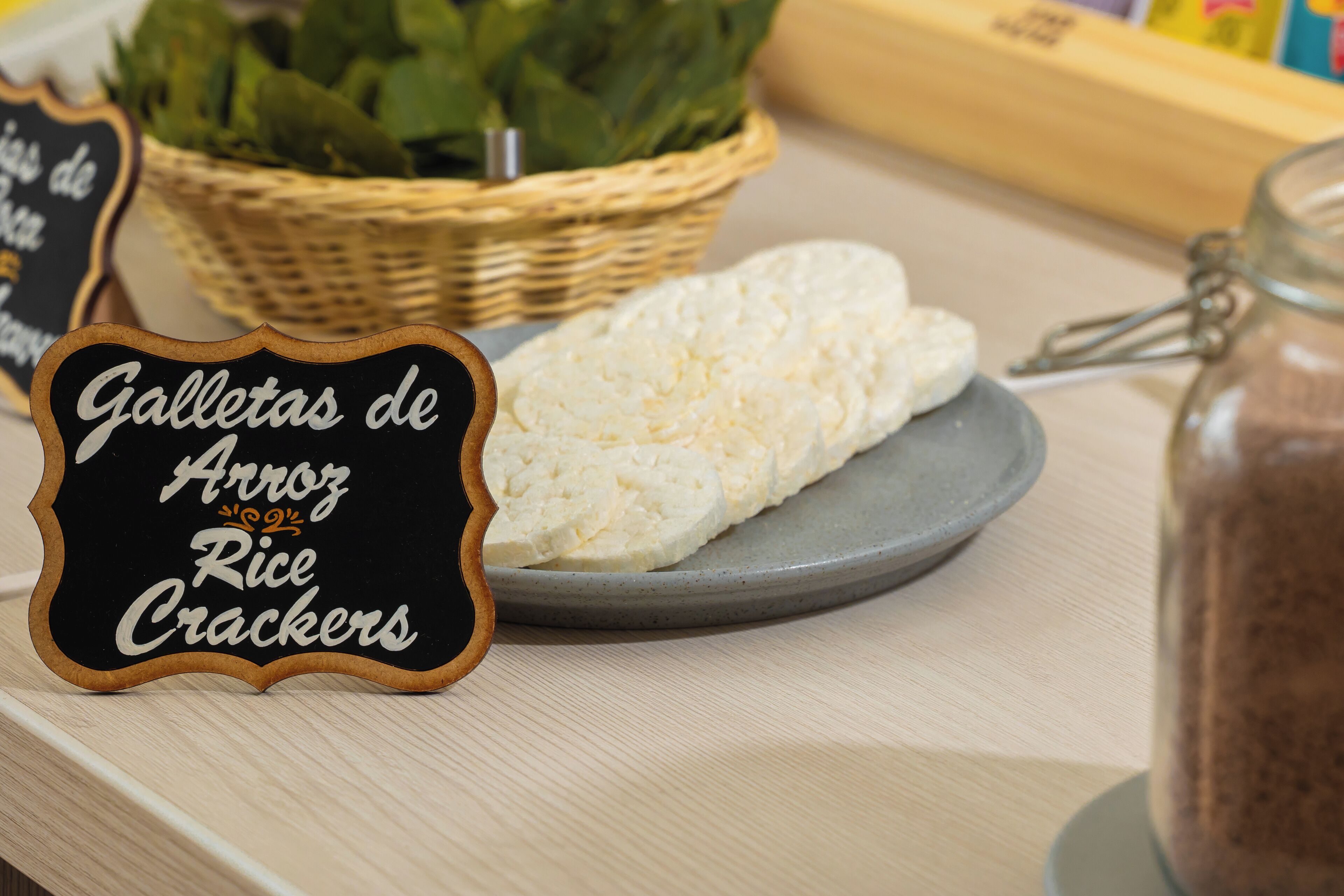 Une pancarte indiquant « Galletas de Aeroz, biscuits de riz » est placée à côté d’une assiette de biscuits blancs et d’un pot de pâte à tartiner au chocolat.