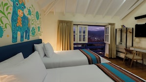 A hotel room with a large bed, a desk, and a view of the city at night. - 7 Toritos Boutique Hotel (Cusco)