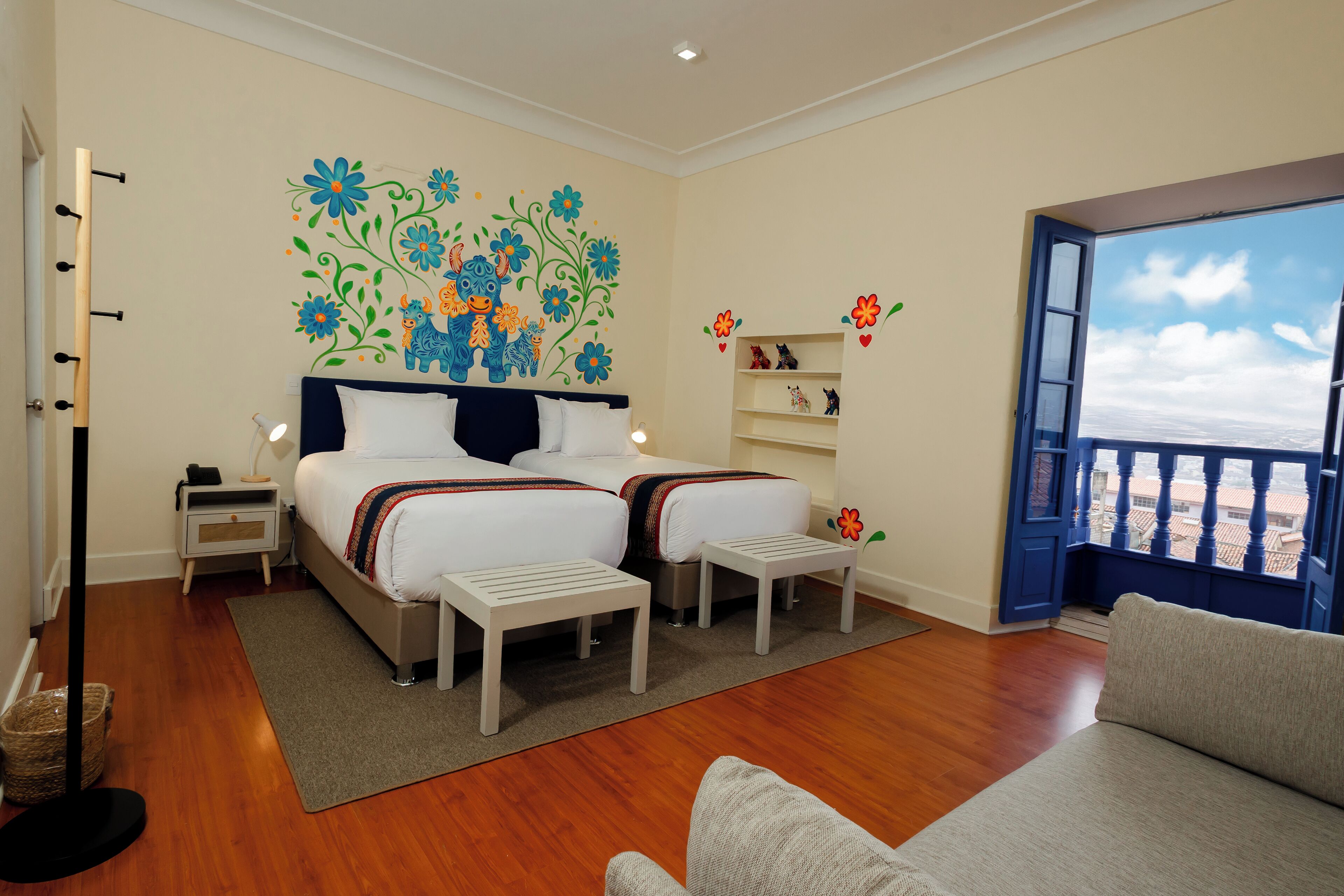 A bedroom with two beds, a nightstand, a bedside table, a small stool, a window with a view, and a balcony.