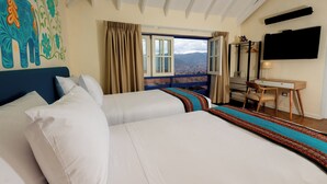 A hotel room with a large bed, a desk, a chair, a TV, and a window with a view of mountains. - 7 Toritos Boutique Hotel (Cusco)