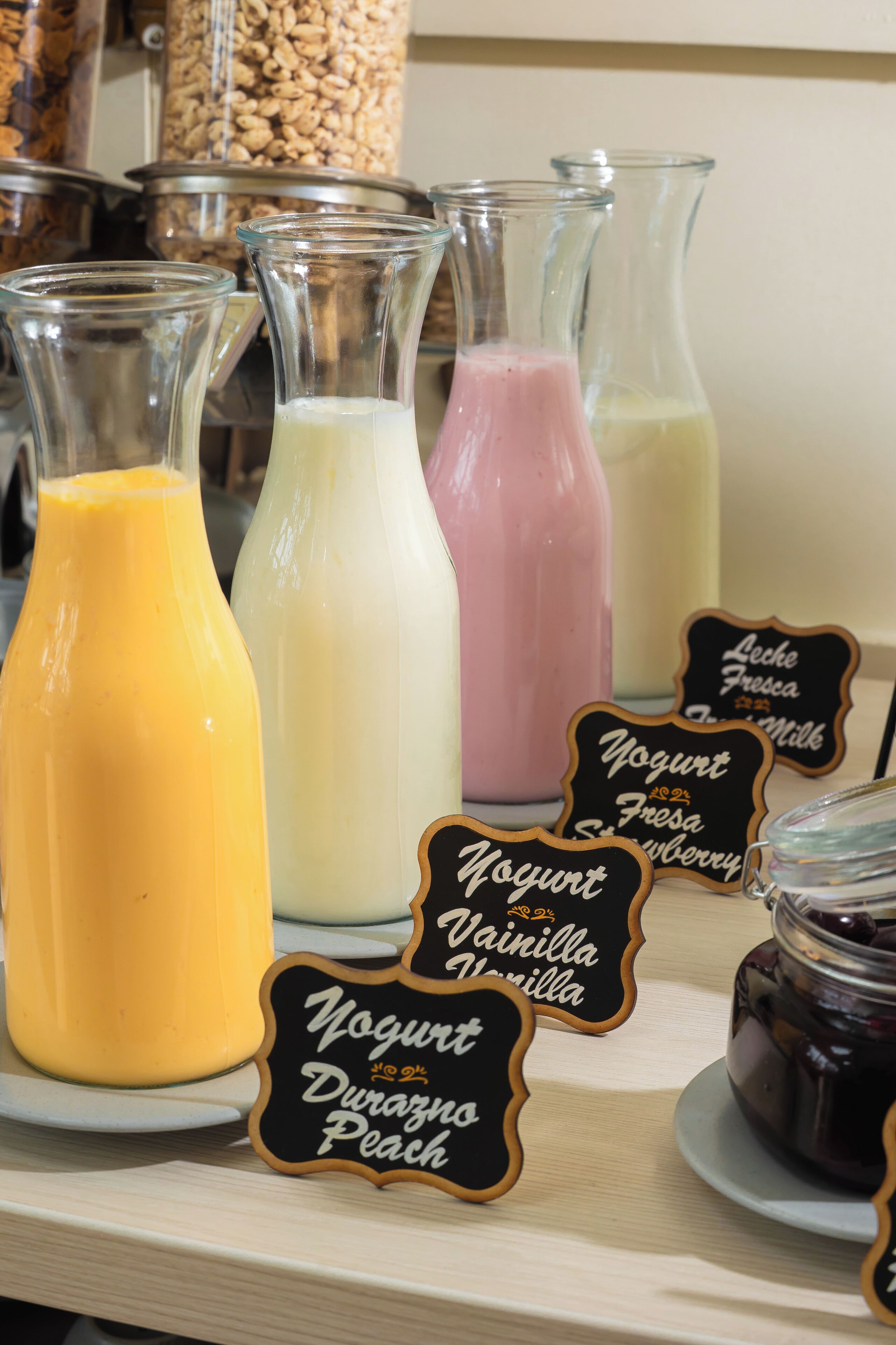 A selection of yogurt drinks in glass bottles with labels indicating flavors like vanilla and peach.