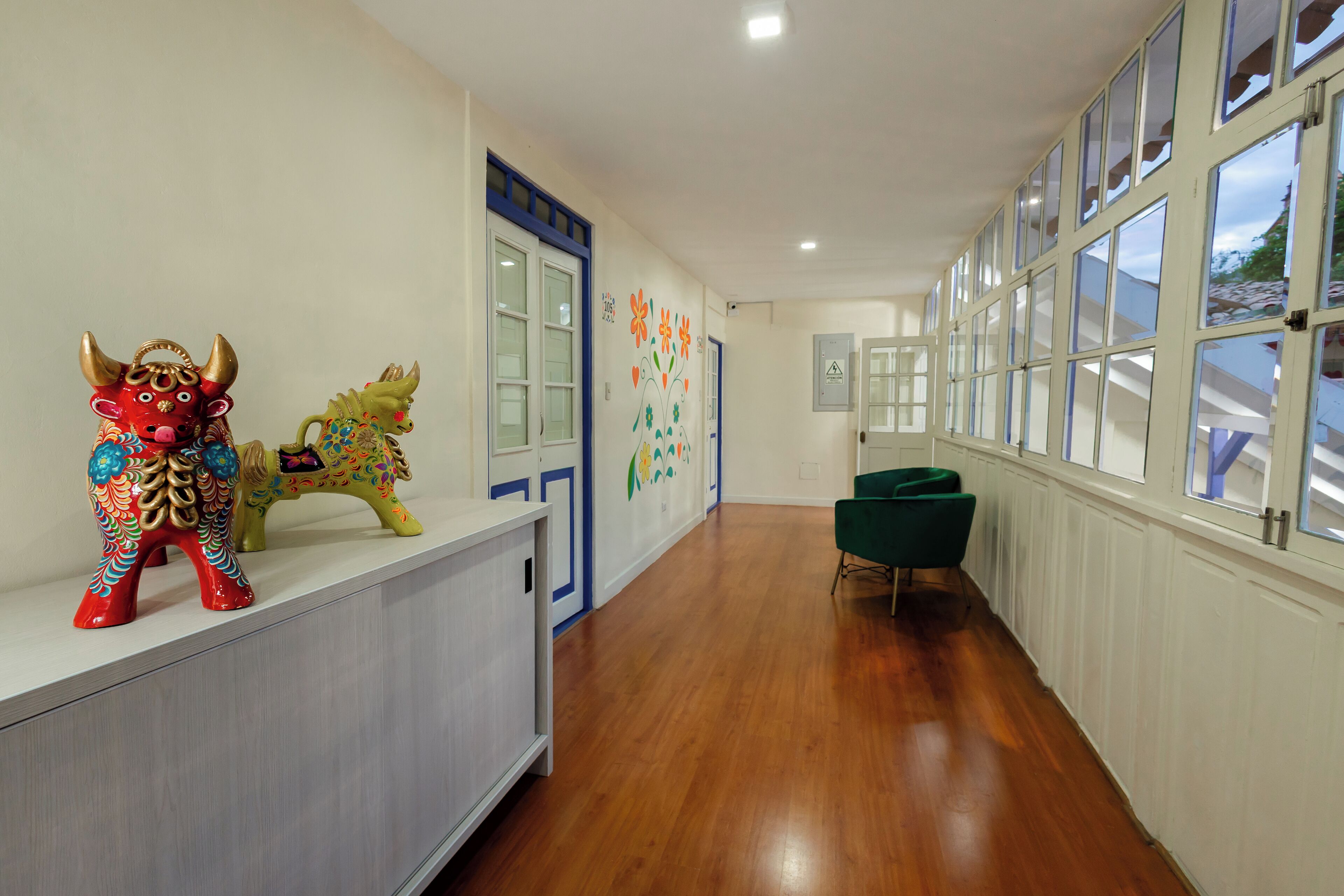 A hallway with a reception desk, colorful wall decorations, and a green chair.