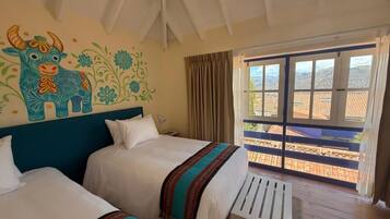 A hotel room with two beds, a balcony with a view of the city, and a mural on the wall.