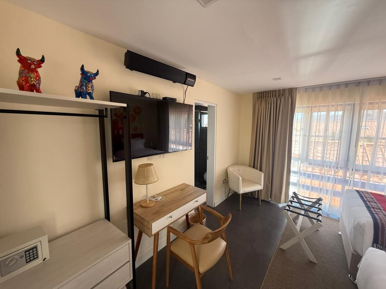 A hotel room with a desk, chair, TV, and a bed.