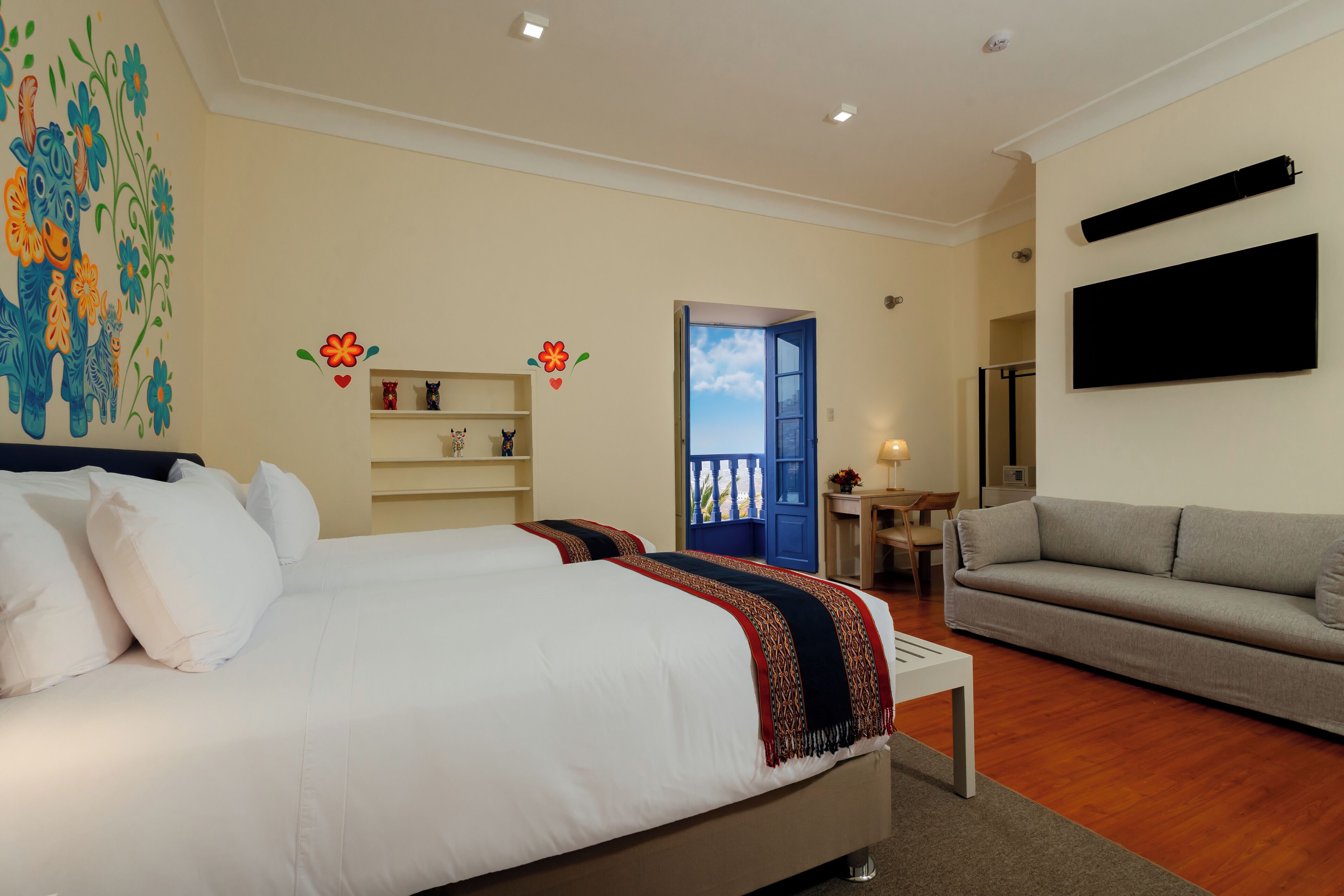 Un dormitorio con una cama grande, un sofá, un televisor y una puerta que da a un balcón.
