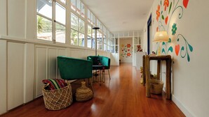 A hallway with large windows, a green chair, wicker baskets, and a wall with floral and heart decorations. - 7 Toritos Boutique Hotel (Cusco)