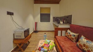 Een knus verblijf met kitchenette, magnetron, bank en een tafeltje met lekkernijen.