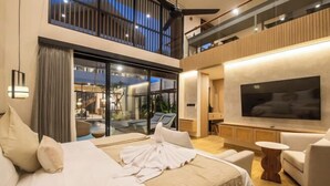 A modern hotel room with a large bed, a TV, and a balcony with a view of the city. - X Samata (Bali)