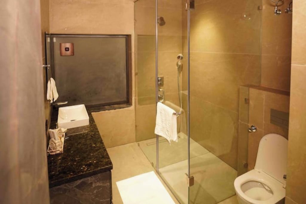A bathroom with a glass-enclosed shower, a toilet, and a sink with a towel rack.