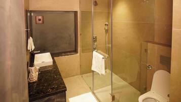 A bathroom with a glass-enclosed shower, a toilet, and a sink with a towel rack.
