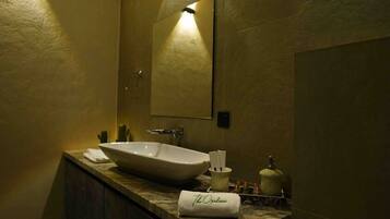 A bathroom with a large vessel sink, a mirror, and a towel with "The Ordnance" written on it.