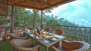 Un espacio comedor al aire libre cubierto, con mobiliario de mimbre y una mesa preparada para dos.