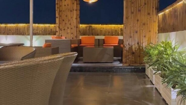 An outdoor seating area with a wooden gazebo, cushioned chairs, and a tiled floor. - 3 Bhk Penthouse|Jacuzzi | Pool Table|The Opulence (panchkula)
