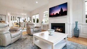 A spacious living room with a fireplace, a large TV mounted above it, and a modern chandelier. - Luxury 2BR/2BA in Thompson’s Station (Thompson`s Station)