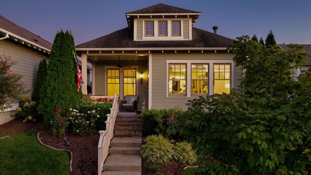 A two-story house with a front porch, a small staircase leading to the entrance, and a well-maintained garden with various plants and flowers. - Luxury 2BR/2BA in Thompson’s Station (Thompson`s Station)