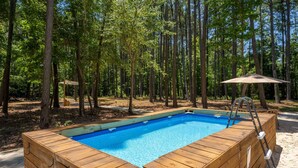 A wooden hot tub surrounded by trees.