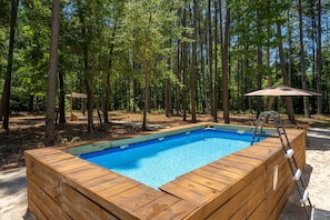 A wooden hot tub surrounded by trees.