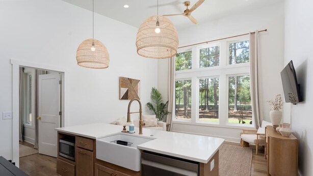A modern kitchen with a central island, wooden cabinets, and a large window with a view of trees.