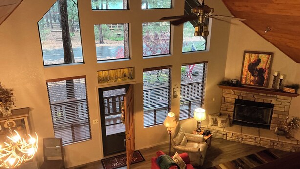 A spacious living room with large windows, a fireplace, and a cozy seating area. - Charming 3-bedroom mountain house in the pines @ Pinetop Country Club (Pinetop Country Club)
