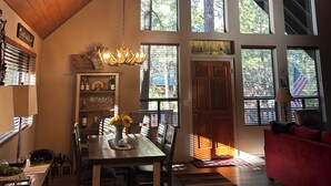 A spacious living area with a high ceiling, large windows, and a dining area with wooden furniture. - Charming 3-bedroom mountain house in the pines @ Pinetop Country Club (Pinetop Country Club)