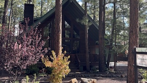 A cabin with a wooden exterior, surrounded by tall pine trees. - Charming 3-bedroom mountain house in the pines @ Pinetop Country Club (Pinetop Country Club)