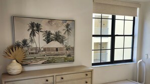 Ein Schlafzimmer mit Bett, Kommode, Bank, Fenster und einem Bild an der Wand.