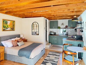 Un dormitorio con cama, mesita de noche y vistas a la cocina.
