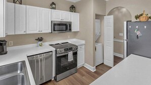 A modern kitchen with white cabinets, stainless steel appliances, and a wooden floor. - Quiet 1st-Floor w/ Pool Views Near Myrtlewood Golf | MW 4665-104 (Myrtle Beach)