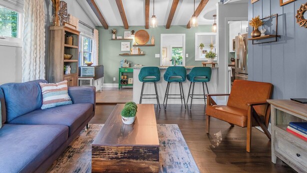 A spacious living room with a blue sofa, a wooden coffee table, and teal chairs. - 3BR Garden Oasis Walk to Light Rail SouthPark & Uptown (Charlotte, North Carolina, United States)