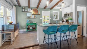 A modern kitchen with a central island, bar stools, and a green accent wall. - 3BR Garden Oasis Walk to Light Rail SouthPark & Uptown (Charlotte, North Carolina, United States)