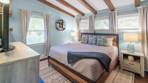 A bedroom with a bed, wooden beams, a nightstand, a lamp, and a window with curtains. - 3BR Garden Oasis Walk to Light Rail SouthPark & Uptown (Charlotte, North Carolina, United States)