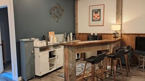 A kitchen with a wooden island, bar stools, a microwave, and a framed sign on the wall. - Forest Nature Retreat with Firepit Near Durham trails and Thermea Spa (Uxbridge)