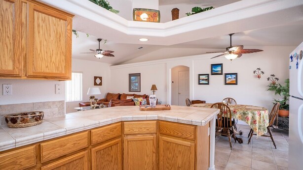 Una cocina con armarios de madera, una isla grande y una zona de comedor con mesa y sillas.