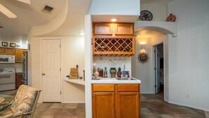 Cozinha com armários de madeira, espaço para vinhos e bancada com diversos objetos.