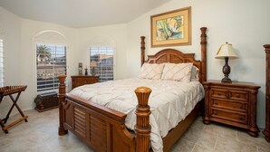 Quarto com cama de madeira, mesa de cabeceira, cômoda e janela com vista.