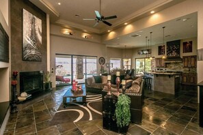 Un vaste espace de vie doté d’une cheminée, de coins salon et offrant une vue sur l’extérieur.