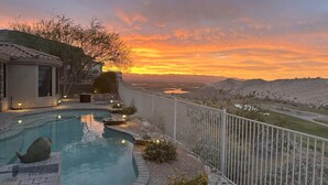 Ein Pool mit Blick auf einen Sonnenuntergang über einer Wüstenlandschaft.