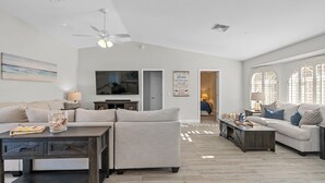 Ein geräumiges Wohnzimmer mit einem großen Deckenventilator, einem Flachbildfernseher und einer gemütlichen Sitzecke mit zwei Sofas und einem Couchtisch.