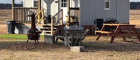 Un petit bâtiment d’un seul étage, doté d’un porche, d’une chaise en bois, d’une table et d’un barbecue.