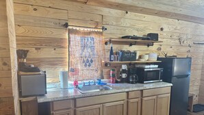 Una cocina con armarios de madera, un refrigerador de acero inoxidable, una cafetera y un microondas.