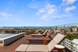 Una terrazza panoramica con poltrone relax e piscina, con vista sulla città.
