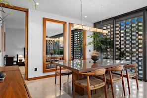 Un comedor moderno con una mesa de vidrio, sillas de madera y un espejo grande.