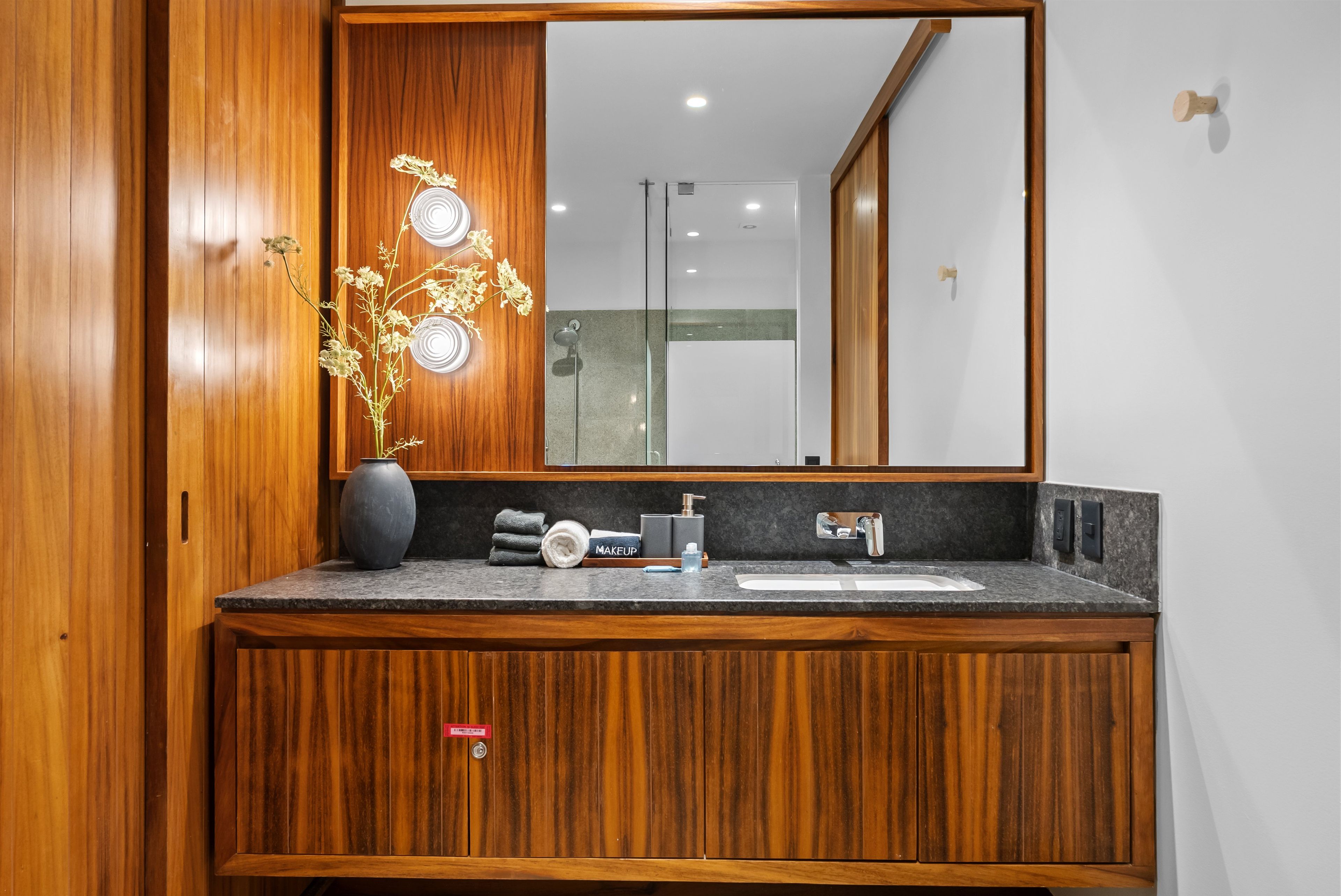 Una cómoda de madera con un espejo grande, un lavabo y un florero con flores.