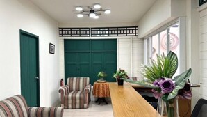 A room with striped sofas, a wooden table, and a green door. - Atlas Hostel Khaosan (Bangkok)