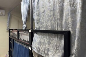 A bunk bed with a patterned curtain and a blue curtain. - Atlas Hostel Khaosan (Bangkok)