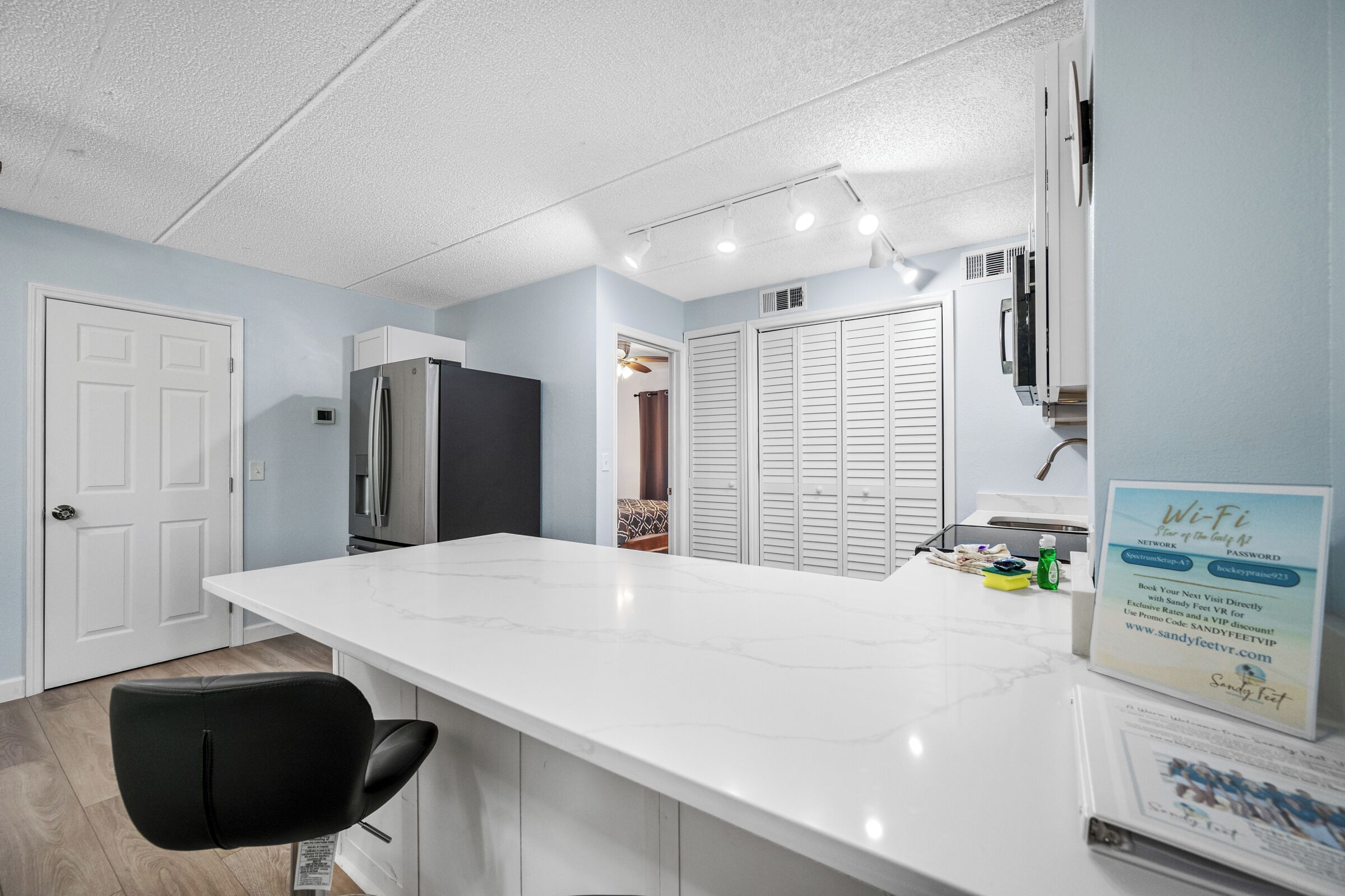 A kitchen with a white countertop, a black chair, a refrigerator, and a Wi-Fi sign.