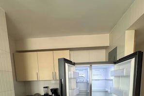 A modern kitchen with white cabinets, a built-in refrigerator, and a coffee maker.
