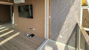 A modern hotel room with a wooden panel wall, a flat-screen TV mounted above a carpeted area, and a marble accent wall. - 5B - Masterpiece! (Panamá)